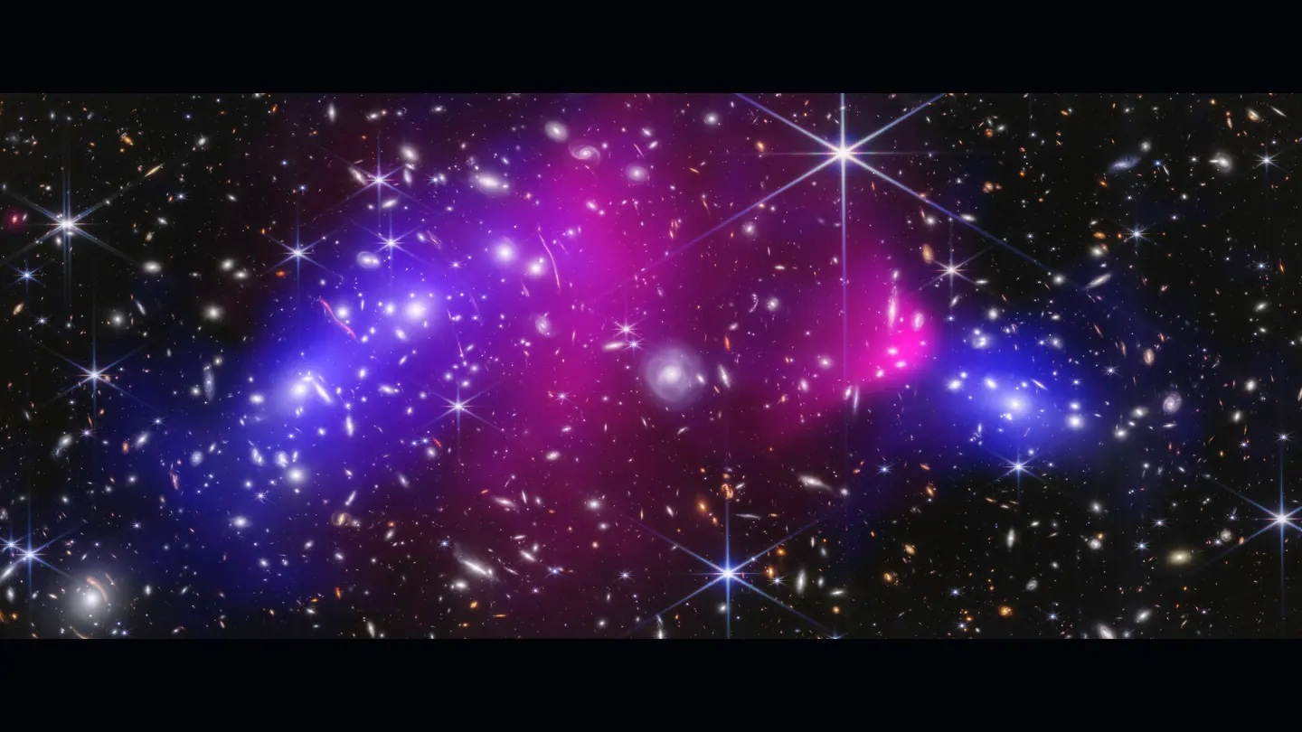 Bullet Cluster composite with many galaxies, pink X-ray gas, and blue lensing-derived mass regions offset from the gas.
